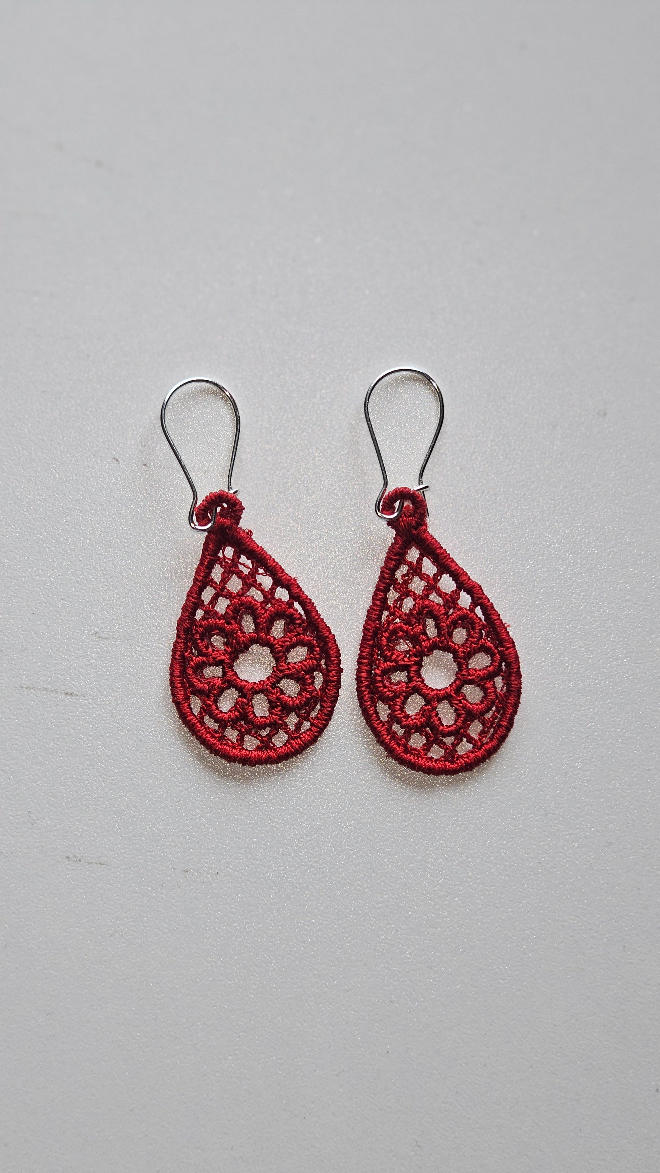 Red lace earrings on a light gray background