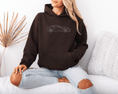 Load image into Gallery viewer, Person wearing a brown hoodie with a car design, sitting on a white couch.
