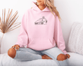 Load image into Gallery viewer, Person wearing a pink hoodie with a car embroidered design sitting on a couch.
