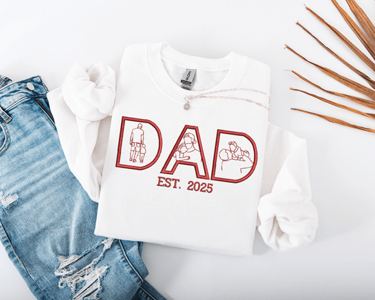 White sweatshirt embroidered with 'DAD EST. 2025' text and embroidered photo outlines on a white background